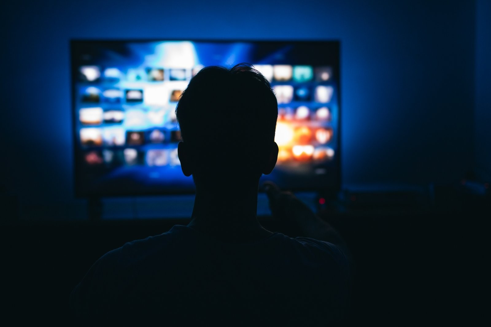 Une personne regarde la TV connectée dans une pièce sombre, le soir